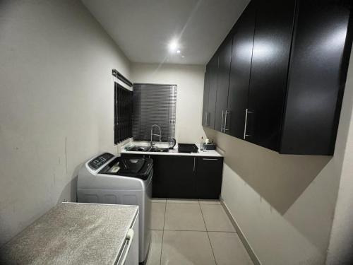 a small kitchen with black cabinets and a dishwasher at Villa on Dirk Smit Crescent in Alberton