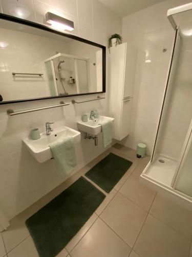 a bathroom with two sinks and a mirror and a shower at Gezellig modern appartement met optie garagebox en in de buurt van strand, winkels en restaurants in Ostend