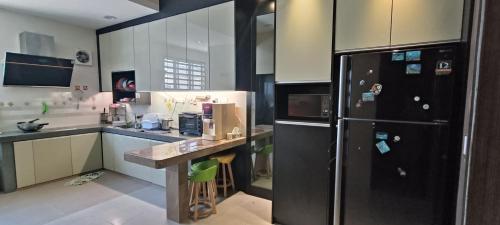 a kitchen with a black refrigerator and a counter at perdana homestay in Ipoh