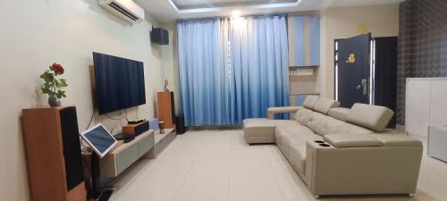 ein Wohnzimmer mit einem Sofa und einem TV in der Unterkunft perdana homestay in Ipoh