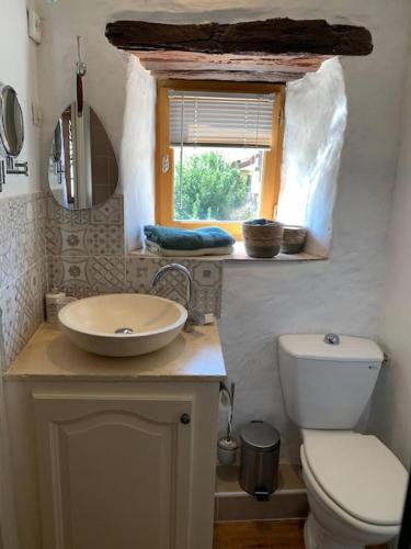 une salle de bain avec un lavabo et des toilettes et une fenêtre dans l'établissement Maison médiévale climatisée avec jardin, à Monpazier