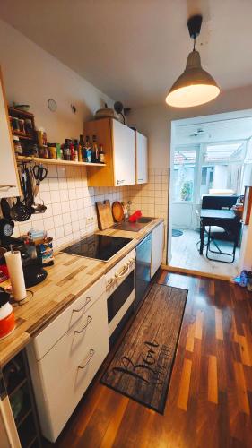 a kitchen with white cabinets and a wooden floor at NEW人 Dachterrasse PRIME/TV 人 4min zum Bhf in Kornwestheim