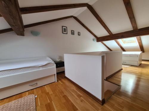 a bedroom with a white bed and a wooden floor at Downtown Apartment Bepi in Opatija