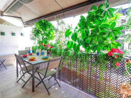 een tafel en stoelen in een kamer met planten bij Flamingo Apartment by Hello Homes Sitges in Sitges