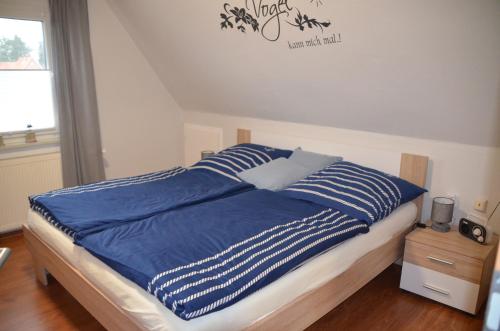 een bed met blauwe en witte lakens en een raam bij FeWo Deichblick Wischhafen in Wischhafen