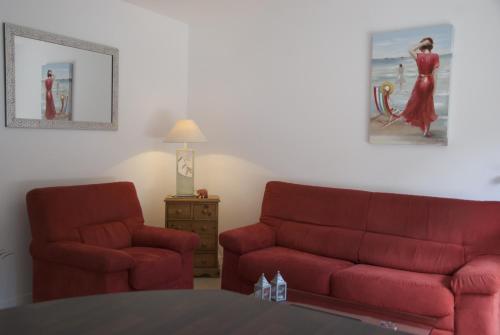 a living room with a red couch and a chair at Gîte La Terrasse Du Verger in Carquefou
