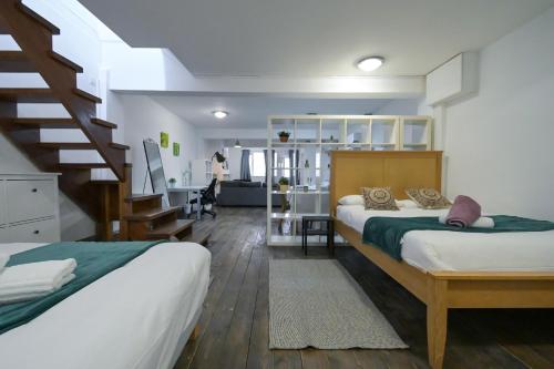 1 dormitorio con 2 camas y escalera en Stoke Newington Studio by DC London Rooms en Londres