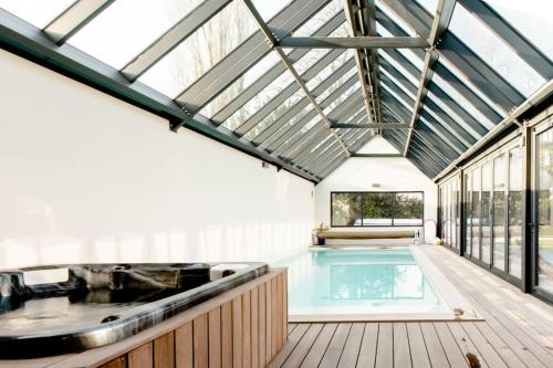 - une piscine dans une maison avec un toit dans l'établissement Écurie Les Tourelles Piscine intérieure & spa, à Gainneville