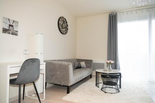 a living room with a couch and a chair and a table at L’Élégant - T2 - 10 min aéroport - Parking privé in Lingolsheim
