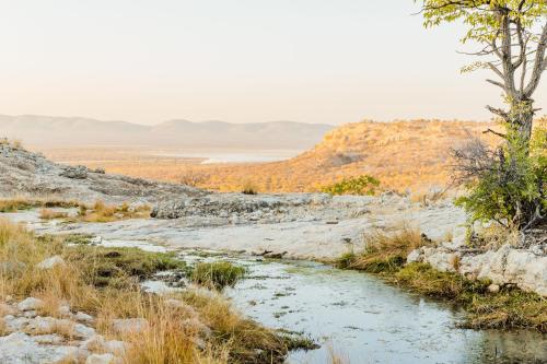 a river in the desert with mountains in the background at Munsterland Guest Farm in Outjo