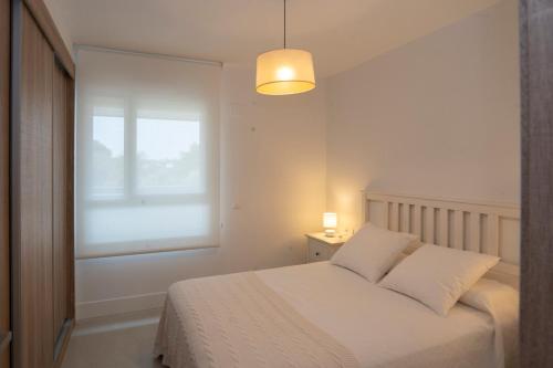 ein weißes Schlafzimmer mit einem Bett und einem Fenster in der Unterkunft Sotogrande San Roque Cádiz in San Roque