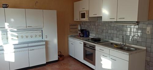 una cucina con armadi bianchi e lavandino di Ferienwohnung Marie a Nohfelden