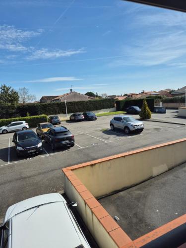 un estacionamiento con autos estacionados en un estacionamiento en appart cosy proche zone aéronautique, en Tournefeuille