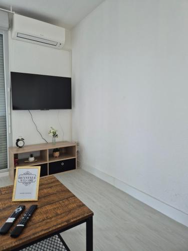 appart cosy proche zone aéronautique في تولوز: غرفة مع طاولة وتلفزيون على الحائط