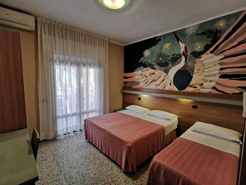 una camera d'albergo con due letti e un dipinto sul muro di Hotel Pine Beach a Rosolina Mare