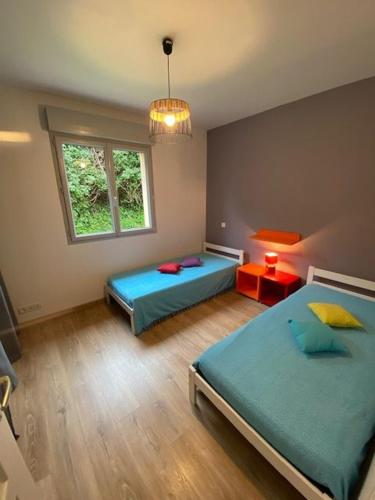 une chambre avec deux lits et une fenêtre dans l'établissement lemarinel, à Barneville-Carteret