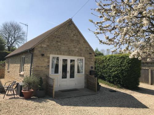 un pequeño edificio de ladrillo con una puerta blanca en Cherry Tree Cottage in idyllic Cotswold village, en Chipping Norton