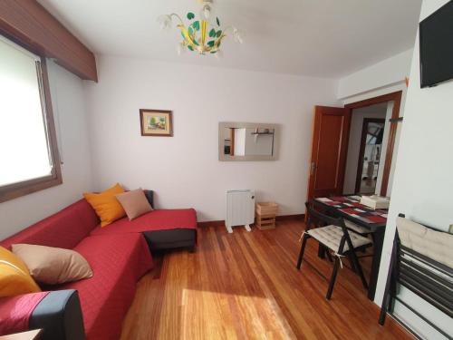 a living room with a red couch and a table at Erkiaga Etxea in Lekeitio
