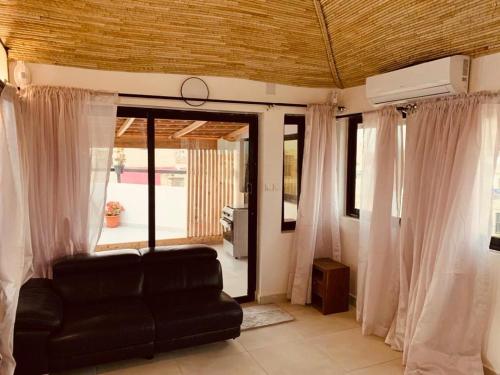 ein Wohnzimmer mit einem schwarzen Sofa und Vorhängen in der Unterkunft Résidence Kali in Guediawaye