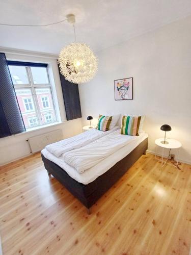 - une chambre avec un grand lit et un lustre dans l'établissement Charming Apartment On Pedestrian Street Randers, à Randers