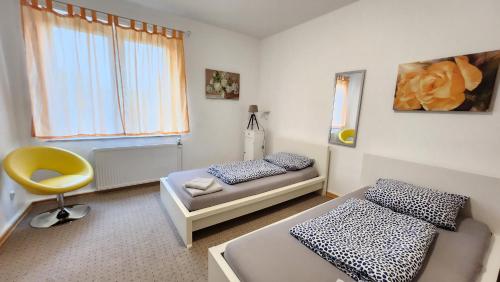 ein Schlafzimmer mit 2 Betten und einem gelben Stuhl in der Unterkunft ELENA flat IRIS, Oberhausen Zentrum CentrO Westfield in Oberhausen