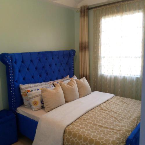 a bed with a blue head board and a window at Verona Airbnb in Thika