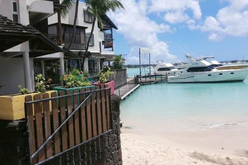 a boat is docked next to a beach with a house at Superb one bedroom apartment in Grand-Baie