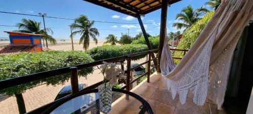 a balcony with a hammock and a beach at Pousada Enseada do Gostoso in São Miguel do Gostoso