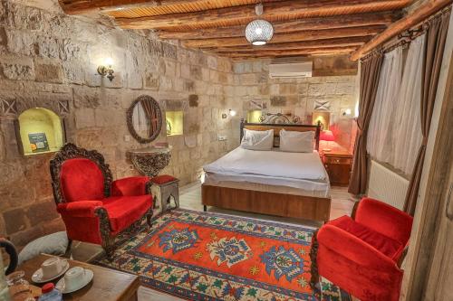 1 dormitorio con 1 cama y 2 sillas rojas en Bedrock Cave Hotel, en Göreme