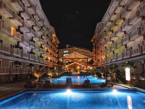 a swimming pool in the middle of two buildings at night at Closest Studio with Balcony from Cebu Airport in Lapu Lapu City