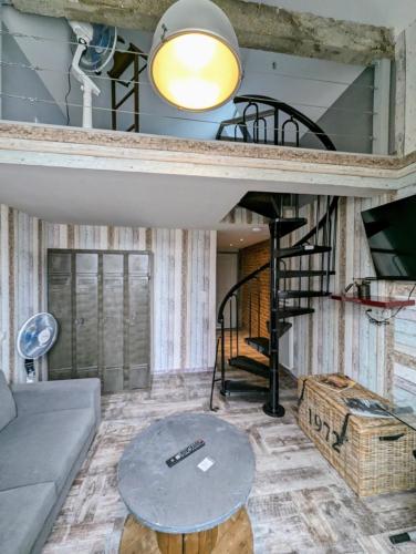 a living room with a couch and a spiral staircase at Chambres d'Hôtes La Filature in Saint-Quentin