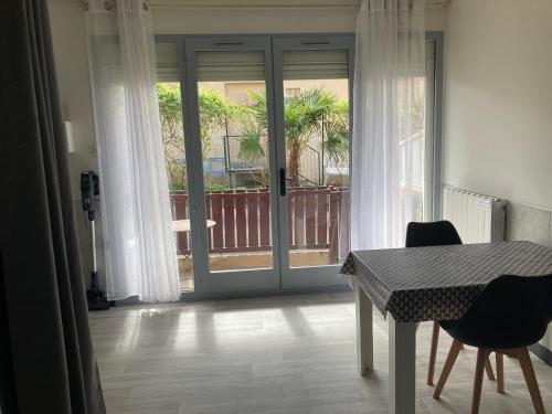 d'une chambre avec une table, des chaises et une porte coulissante en verre. dans l'établissement Le Beaulieu appartement T1 Bis RDC classé 3 étoiles avec parking à Barbotan, à Cazaubon