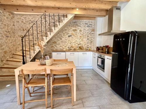 - une cuisine avec une table en bois et un réfrigérateur noir dans l'établissement Arles fait sa révolution, à Arles