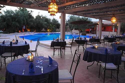 a restaurant with tables and chairs in front of a pool at La Maison Des Oliviers in Marrakesh