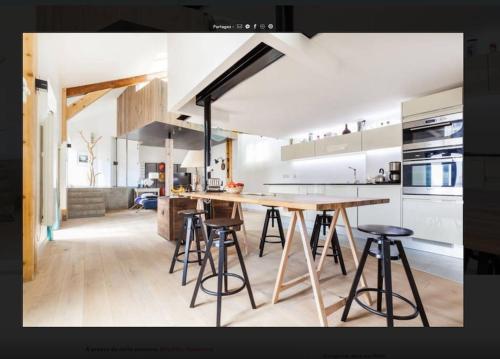 - une cuisine avec une table en bois et quelques tabourets dans l'établissement Loft proche Paris, Charpente apparente, à Pantin