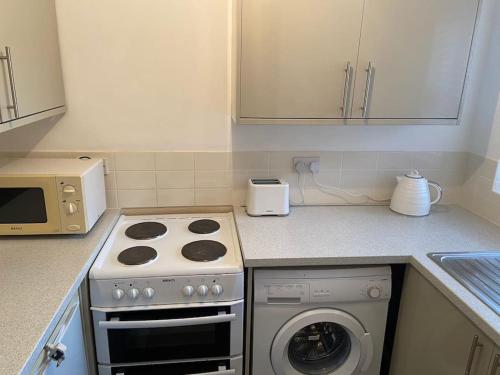 a kitchen with a stove and a washing machine at One bedroom ground floor flat central Chichester in Chichester