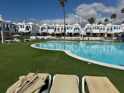 a resort with a large swimming pool with lounge chairs at 55 PLAYMAR VILLA WELLNESS in Maspalomas