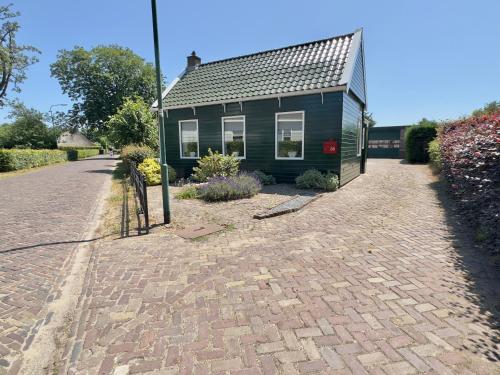 a small green house on a brick road at Vakantiehuis 't Hofje nabij dorpscentrum en strand in Castricum