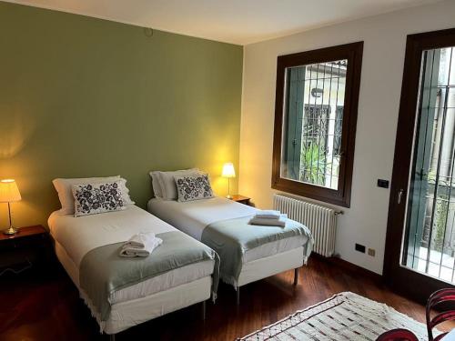 a bedroom with two beds and two windows at Il Portico. Charm apartment, Vicenza downtown. in Vicenza