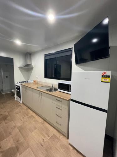 a kitchen with a white refrigerator and a sink at Horseshoe Tourist Park in Wagga Wagga