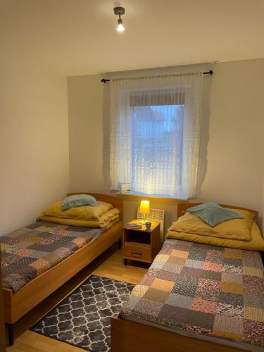 two beds in a small room with a window at Domek wypoczynkowy Leszek in Żarnowska