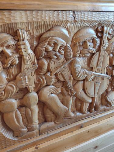 een houten muur met een houtsnijwerk van mannen die muziek spelen bij Apartamenty u drwala in Zakopane