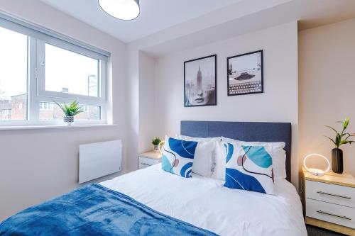 The Belfry - Deluxe 2 Bedroom 2 Bathroom Apartment في مانشستر: غرفة نوم مع سرير ووسائد زرقاء وبيضاء