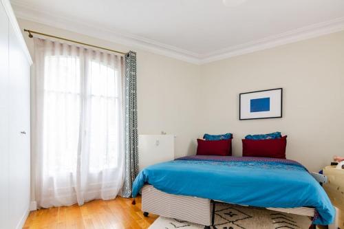 une chambre avec un lit avec des draps bleus et une fenêtre dans l'établissement Appartement en bord de Seine, à Paris