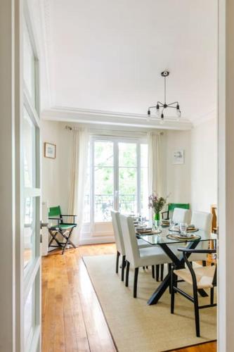 une salle à manger avec une table et des chaises blanches dans l'établissement Appartement en bord de Seine, à Paris