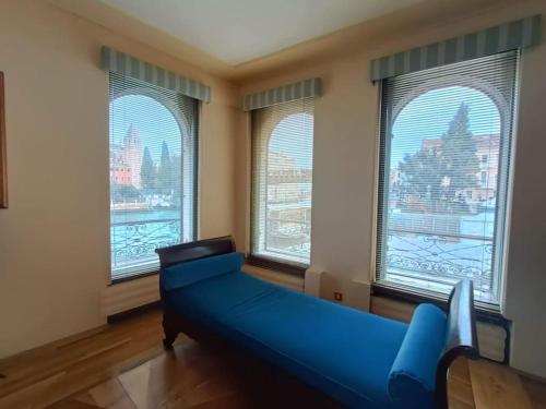 ein Wohnzimmer mit einem blauen Sofa vor den Fenstern in der Unterkunft Palazzo Querini Accademia in Venedig