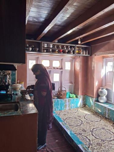a woman standing in a kitchen preparing food at Kahn trekking guesthouse in Nikri Dhokri