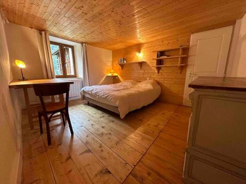 ein Schlafzimmer mit einem Bett und einem Tisch in einem Zimmer in der Unterkunft Mountain house with two barns and a garden in Planay