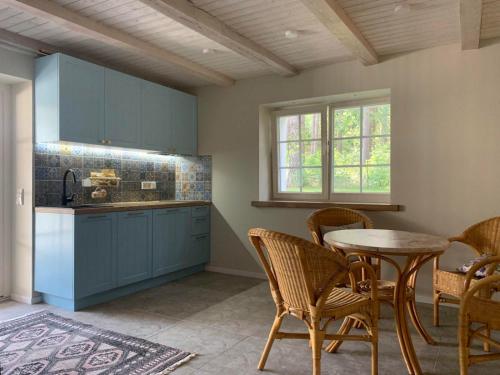 cocina con armarios azules, mesa y sillas en Pušyno apartamentai, en Druskininkai