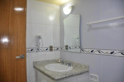 a bathroom with a sink and a mirror at COMODORO DEPARTAMENTOS in Oruro